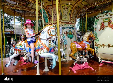 Child riding a hobby horse on gold ornate carousel, fairground in