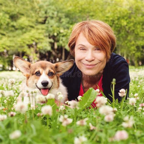Senior Woman With Her Pet Friend Dog On Green Grass In Summer Park