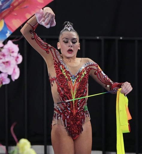 A Woman In A Red And Gold Bodysuit Holding Onto A Yellow Ribbon While