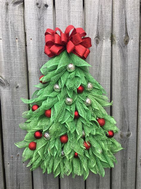 A Christmas Tree Made Out Of Green Leaves And Red Bows On Top Of A