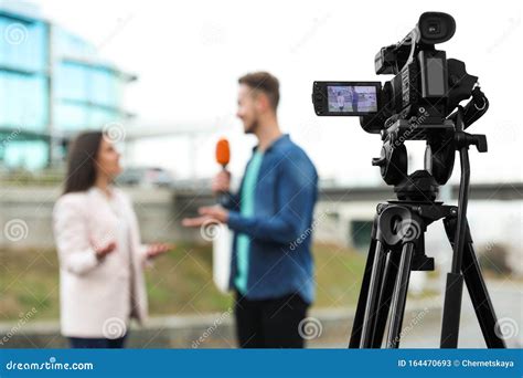 Young Journalist Interviewing Businesswoman On Street Focus On Camera