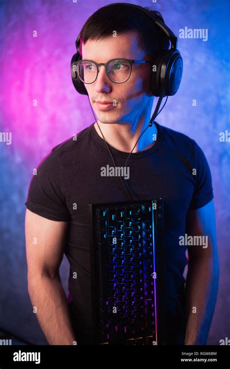 Computer Nerd With Keyboard Over Colorful Pink And Blue Neon Lit Wall Stock Photo Alamy