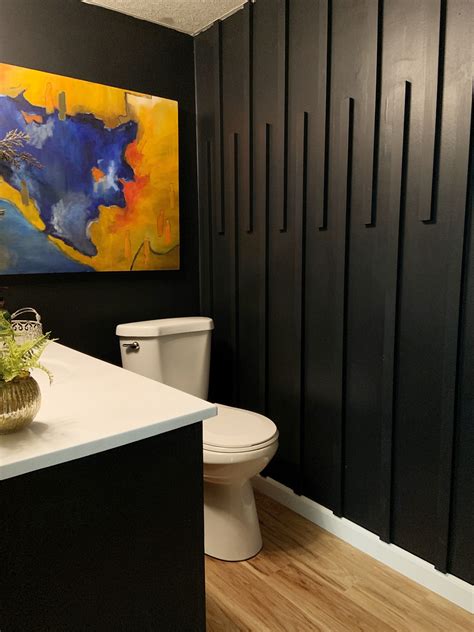 A White Toilet Sitting In A Bathroom Next To A Painting On The Wall