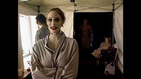 A Woman With Makeup On Her Face Standing In Front Of A Tent