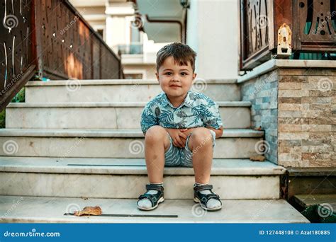 Little L And Very Cute Boy Sitting On The Stairs And Smiling Stock