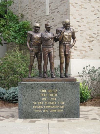 A Statue Of Three Football Players In Front Of A Building