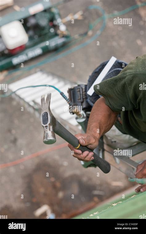 Hispanic Carpenter Climbing Ladder With Hammer And Nail Gun At A House