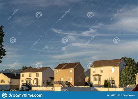 Suburb Homes With Gable Roofs Against Mountain Peak And Blue Sky With