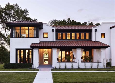 A Large White House With Lots Of Windows And Lights On The Front Door