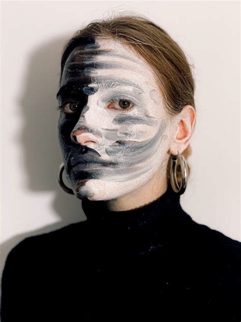 Young woman with contrast dyes on face looking away in white studio ...