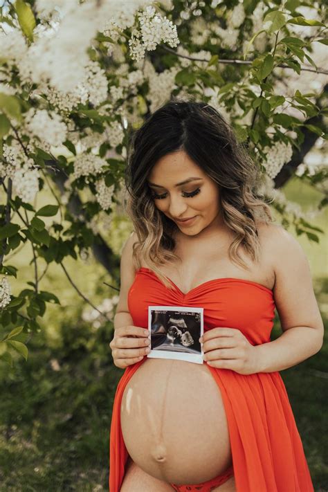 A Pregnant Woman In An Orange Dress Is Holding A Photo
