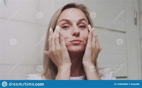 Woman Applying Cream Under The Eyes And Looking At The Camera Stock