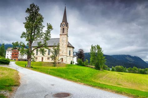 Traditional Alpine Church And Street View With Mountains Dolomites