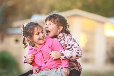 Outdoor Portrait Of Two Young Happy Children Girls Sisters Stock