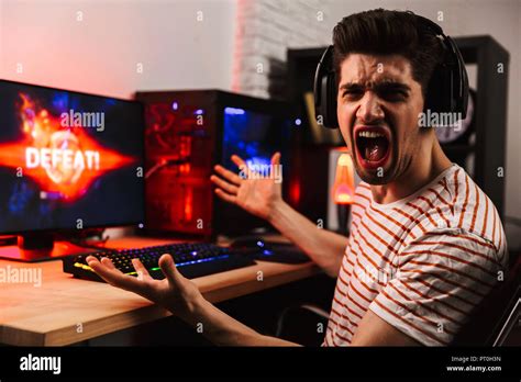 Side View Of Angry Gamer Playing Video Games On Computer And Screaming