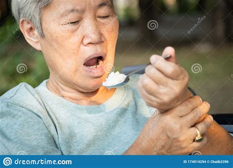 Asian Senior Woman Holding Spoon And Hands Tremor While Eating Rice