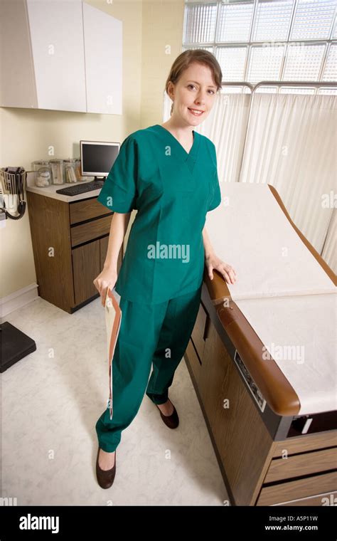 Nurse Wearing Green Scrubs Stands In A Medical Exam Room Stock Photo