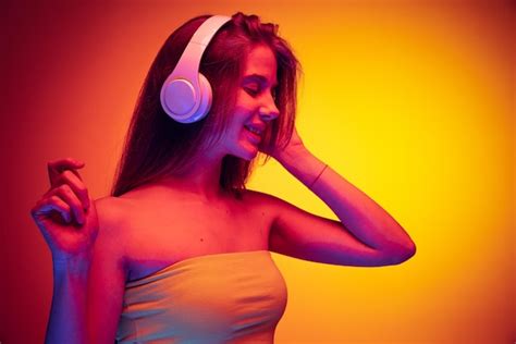 Retrato de uma jovem linda ouvindo música em fones de ouvido dançando