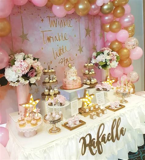 A Table Topped With Lots Of Pink And Gold Desserts Next To A Balloon