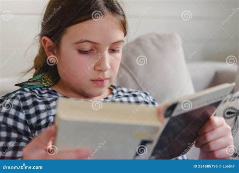 Schoolgirl Reading A Book At Home In A Living Room Reading Assignment