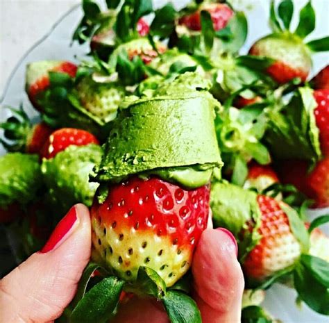 A Person Is Holding Up A Strawberry And Avocado Salad With Strawberries On The Side