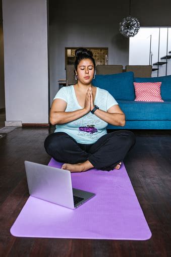 Young Curvy Latin Woman With Computer Sitting On Mat Meditating In