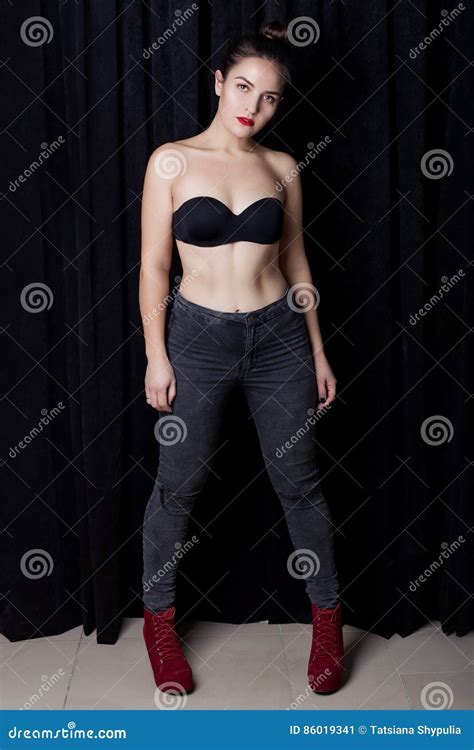 Manierportret Van Sexy Meisje Met Rode Lippen In Zwarte Jeans Met Rode Schoenen Op Een Zwarte
