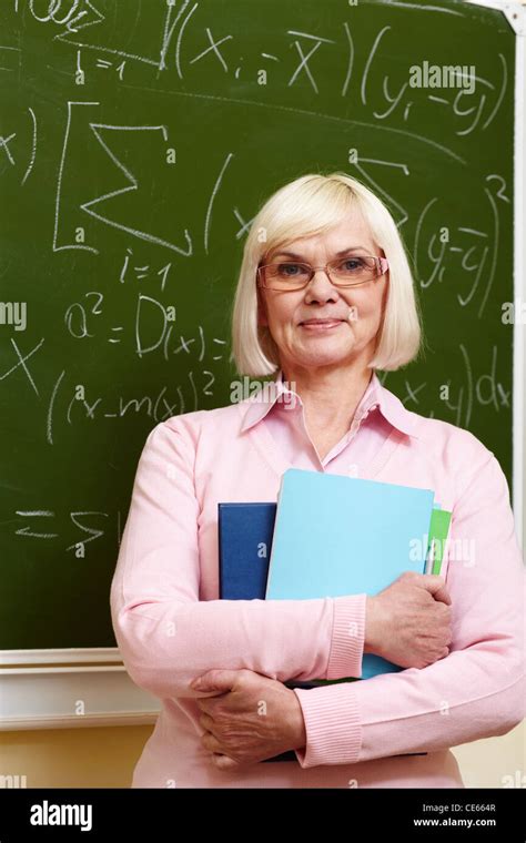 Portrait Of Mature Teacher With Copybooks Looking At Camera With
