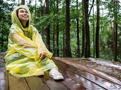 happy asian woman wearing yellow raincoat sit on wooden floor under rain stock image image of