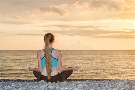 Woman Meditating On The Beach In Lotus Position Sunset Stock Image