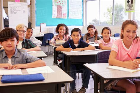 Smiling Elementary School Kids Sitting At Desks In Classroom Stock