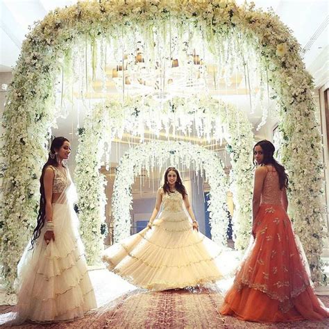 Three Women Standing In Front Of A Floral Archway