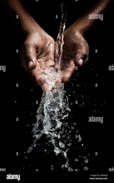 Indian Mans Cupped Hands Catching Poured Water Against Black Background