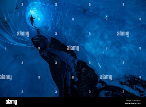 A Deep Dark Ice Cave With A Man Standing In The Back He Is