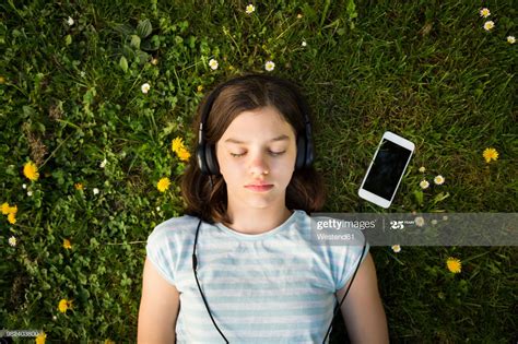 Portrait Of Girl Lying On Meadow Listening Music With Headphones And