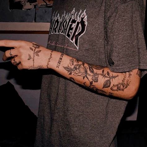 A Man With Tattoos On His Arm Pointing At Something