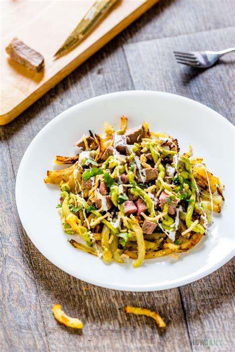 Next, on a lined baking sheet, add a pile of the baked homemade fries, then top with sliced carne asada steak and then top with shredded cheese. Tasty Carne Asada Fries Recipe with Mexican Style Steaks