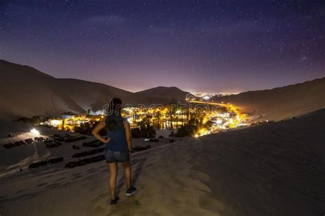 Female Relaxing On The Sand Dune Admiring The Oasis Town Of Huacachina