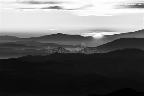 Distant Sunset Above Layers Of Mountains And Valleys With Mist And Fog