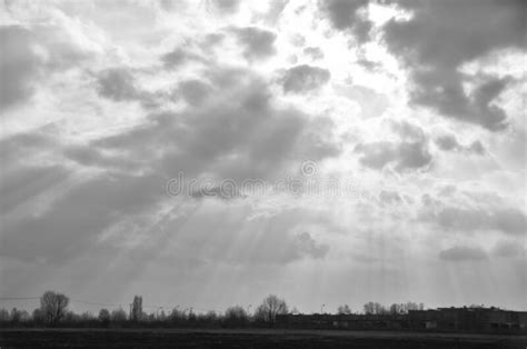 The Sun Shines Through The Clouds In Single Streaks Over The Field