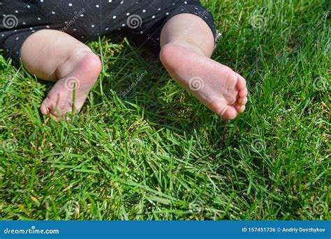 Little Child On The Grass Baby Feet On The Green Grass In The Park
