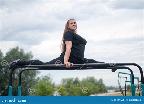 A Beautiful Smiling Overweight Young Woman Stretches For Split On