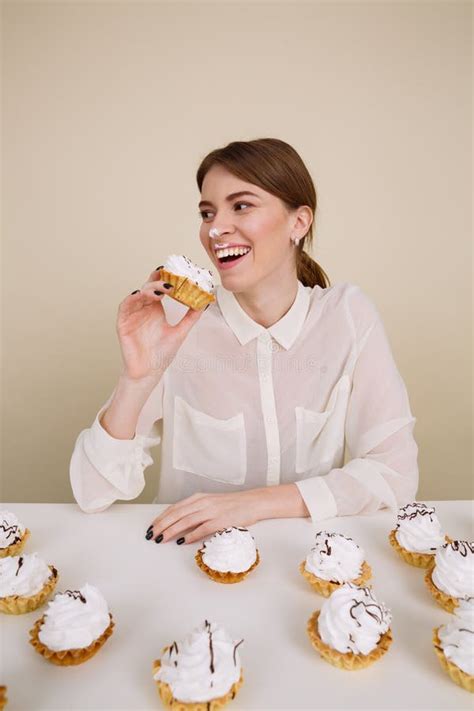 Cheerful Funny Young Woman Eating Cakes And Laughing Stock Photo