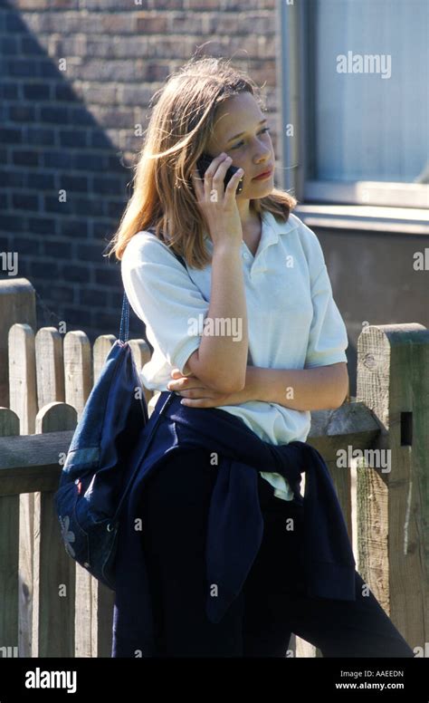 Blonde Teenage Secondary Schoolgirl In Uniform Talking On Her Mobile Phone Outside School Stock