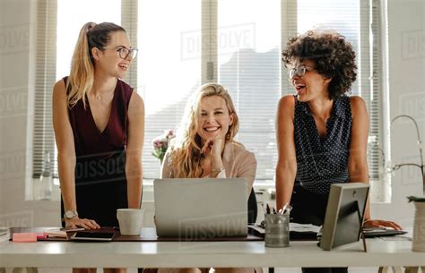 Smiling Young Women At Work Desk At Office Group Of Three