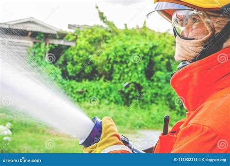 Firefighters Holding Firehose To Extinguish Fire Stock Photography