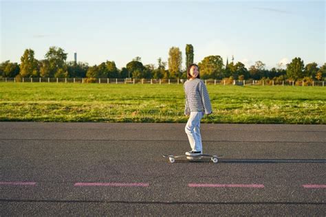 Beautiful Asian Skater Girl Riding Her Longboard On Sunny Empty Road Young Woman Enjoying Her