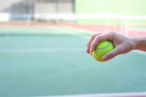 Premium Photo Hand Holding Tennis Ball On Court Background