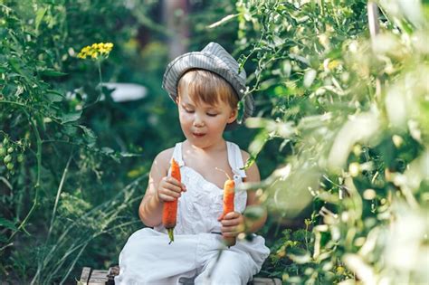 Premium Photo Baby Farmer With Carrots And Cacual Clother Sitting In