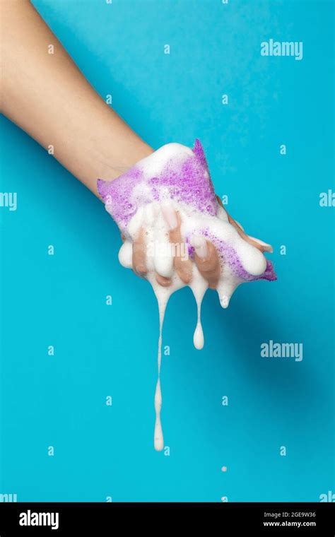 Hand Of Crop Anonymous Female Squeezing Bath Sponge With White Foam